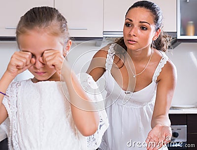 Mother shaming daughter for misbehaviour in domestic interior Stock Photo