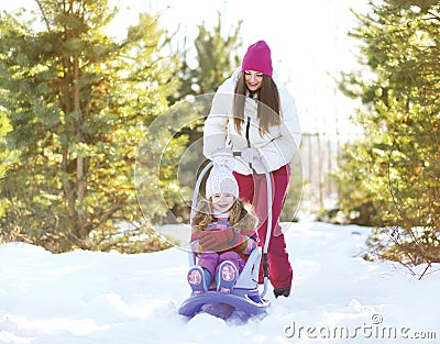 Mother sledding child in sunny winter Stock Photo