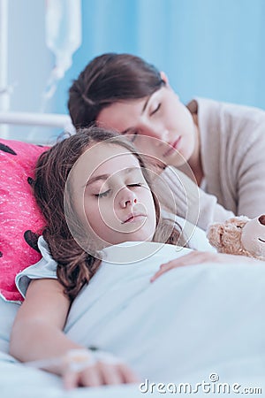 Mother sleeping with sick daughter Stock Photo