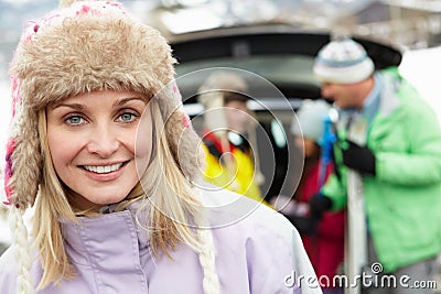 Mother Smiling At Camera Whilst Family Load Skis Stock Photo