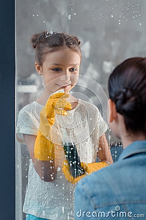 Mother and smiling daughter in protective gloves washing window Stock Photo