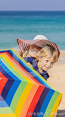 Mother and son on the beach in a hat and beach umbrella VERTICAL FORMAT for Instagram mobile story or stories size Stock Photo