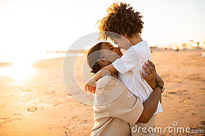 Mother and son conncection. Loving african american mother and her son bonding outdoors while walking by seaside Stock Photo