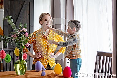 Mother and son are decorating a table with paper eggs for Easter. Indoor Stock Photo