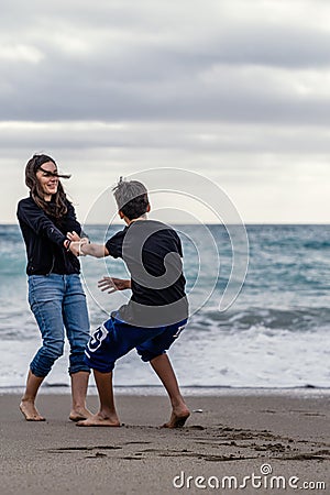 Mother and son enjoying themselves on the beach on a winter day. Vertical shot Stock Photo