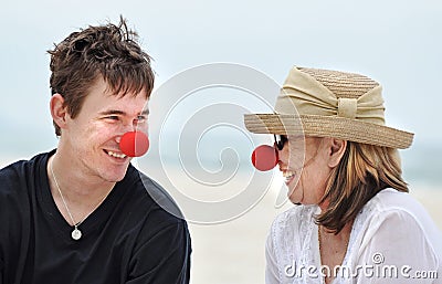 Mother and son having fun laughing celebrating red nose day on beautiful beach holiday Stock Photo