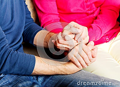 Mother and son sitting on couch and holding hands Stock Photo