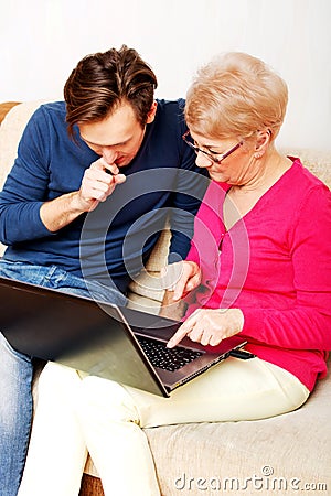 Mother and son sitting on the couch and watching something on laptop Stock Photo