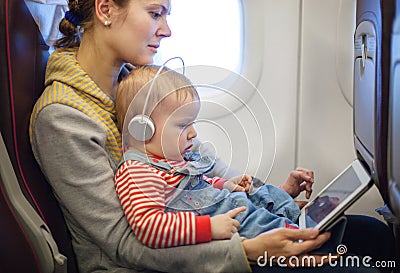 Mother and son using tablet on board of airplane Stock Photo