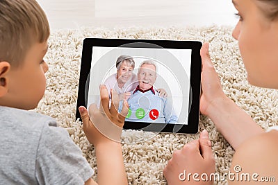 Mother And Son Videoconferencing On Digital Tablet Stock Photo