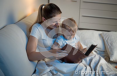 Mother storytelling to her adorable baby boy at bed before going Stock Photo