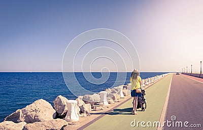 Mother strolling with newborn in a coast long road Stock Photo