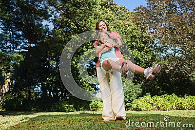 Mother swinging her daughter around having fun Stock Photo