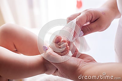 The mother takes care of the baby skin and wipes the baby`s feet with wet wipes Stock Photo