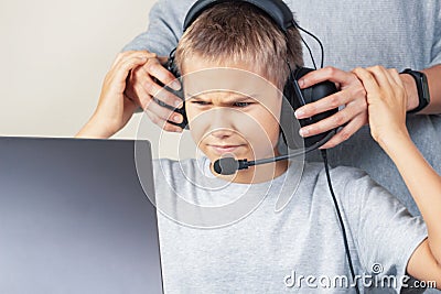 Mother takes off headphones her angry teenage son. Computer games addiction Stock Photo