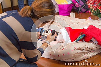 Woman taking photo of baby wearing Santa Claus hats, with smartphone Stock Photo