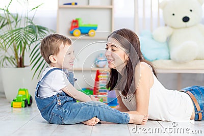 The mother talks to the baby boy or plays at home with educational toys in the children`s room. A happy, loving family Stock Photo