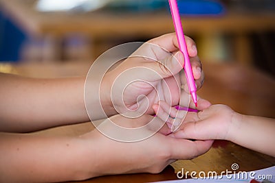 Mothers or adults use a soft pink magic pen to write onto the skin of the daughters hands or young children gently. Stock Photo
