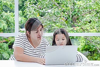 Mother taught a young Asian daughter to study online at home using a notebook computer. Stock Photo