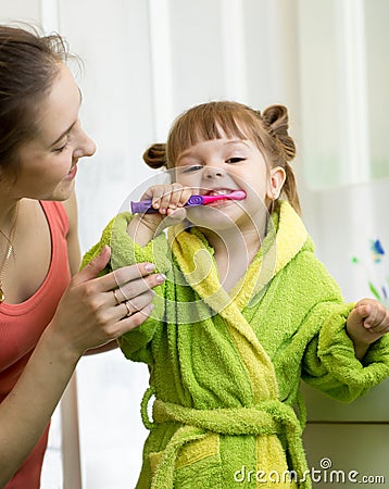 Mother teaches her little daughter how to brush teeth Stock Photo