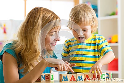 Mother teaches son child to read letters and words playing with cubes Stock Photo