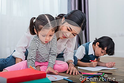 Mother teaching children in drawing class. Daughter and son painting with colorful crayon color in home. Teacher training students Stock Photo
