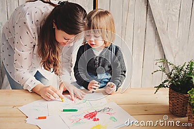 Mother teaching toddler boy to draw with pencils at home Stock Photo