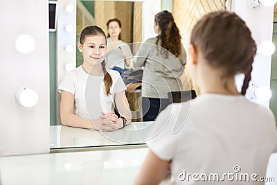 Mother and teenager girl preparing for photoshooting in dressing room in front of mirror Stock Photo