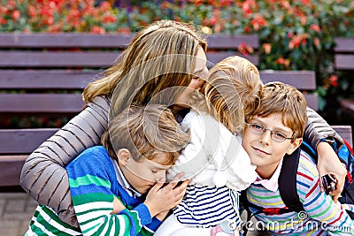 Mother and three children hugging. Happy family sitting outdoor: woman and two brother kids boys and cute little toddler Stock Photo