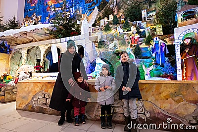 Mother with three children visit Christmas nativity crib scene in church Editorial Stock Photo