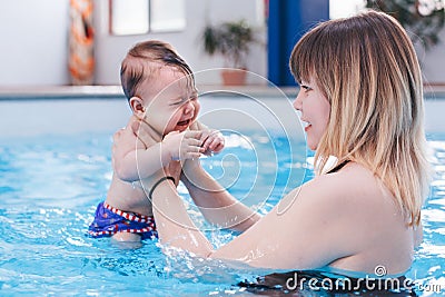 Mother traning her newborn baby to float in swimming pool Stock Photo