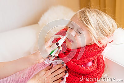 Mother treating her child`s runny nose with nasal spray Stock Photo