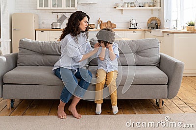 Mother trying to distract upset kid. Young mom engaging depressed offended son in bad mood by hug Stock Photo