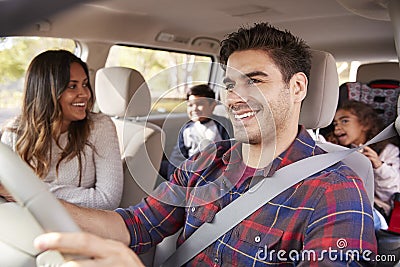 Mother turns around to her children on the back seat of car Stock Photo