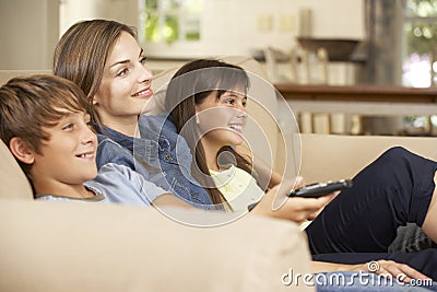 Mother And Two Children Sitting On Sofa At Home Watching TV Together Stock Photo