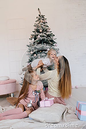 Mother and two daughters playing at at home near Christmas tree. happy family have fun for the Christmas holidays Stock Photo