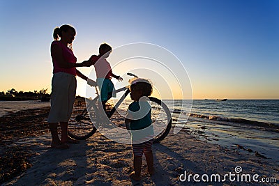 Mother with two kids biking at sunset Stock Photo