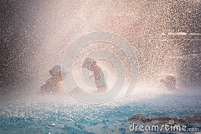 Mother with two kids splashed by water in the pool Stock Photo