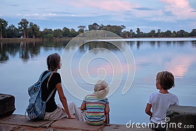 Mother and two sweating tired sons rest evening sunset near lake. Angkor Wat, Cambodia Stock Photo