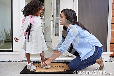 Mother Tying Daughters Shoelaces As She Leaves For School Stock Photo