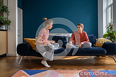 Mother and upset teenage daughter sitting on sofa having difficult conversation at home Stock Photo