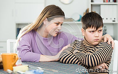 Mother wants to talk with his son after conflict at table Stock Photo