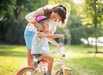 Mother wearing helmet on baby girl on bicycle Stock Photo