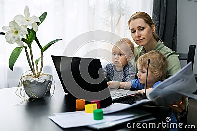 Mother working from home. using laptop at desk with kids on her lap Stock Photo
