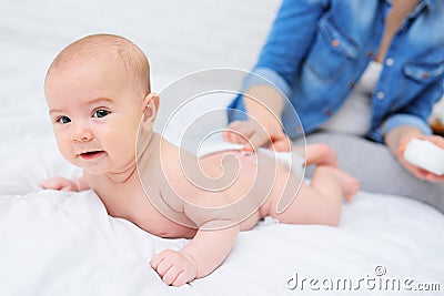 mother& x27;s hand applies a moisturizing baby cream to the baby boy& x27;s skin. Hygiene of the newborn child. Stock Photo