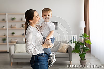 Mother& x27;s love. Young mom holding toddler son on hands, little kid looking at camera and smiling, free space Stock Photo