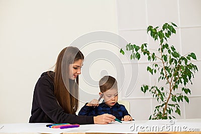 Mother and young son draws a picture at the table Stock Photo