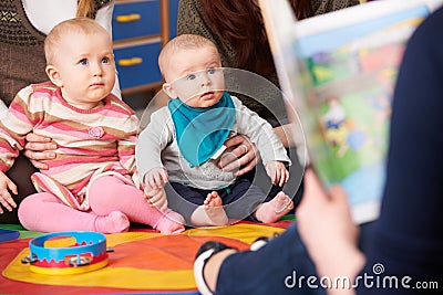 Mothers With Children At Baby Group Listening To Story Stock Photo