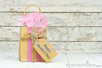 Mothers Day gift bag with tag against rustic white wood Stock Photo