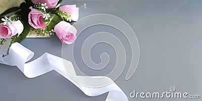 Silk ribbon, pink roses on grey background. Stock Photo